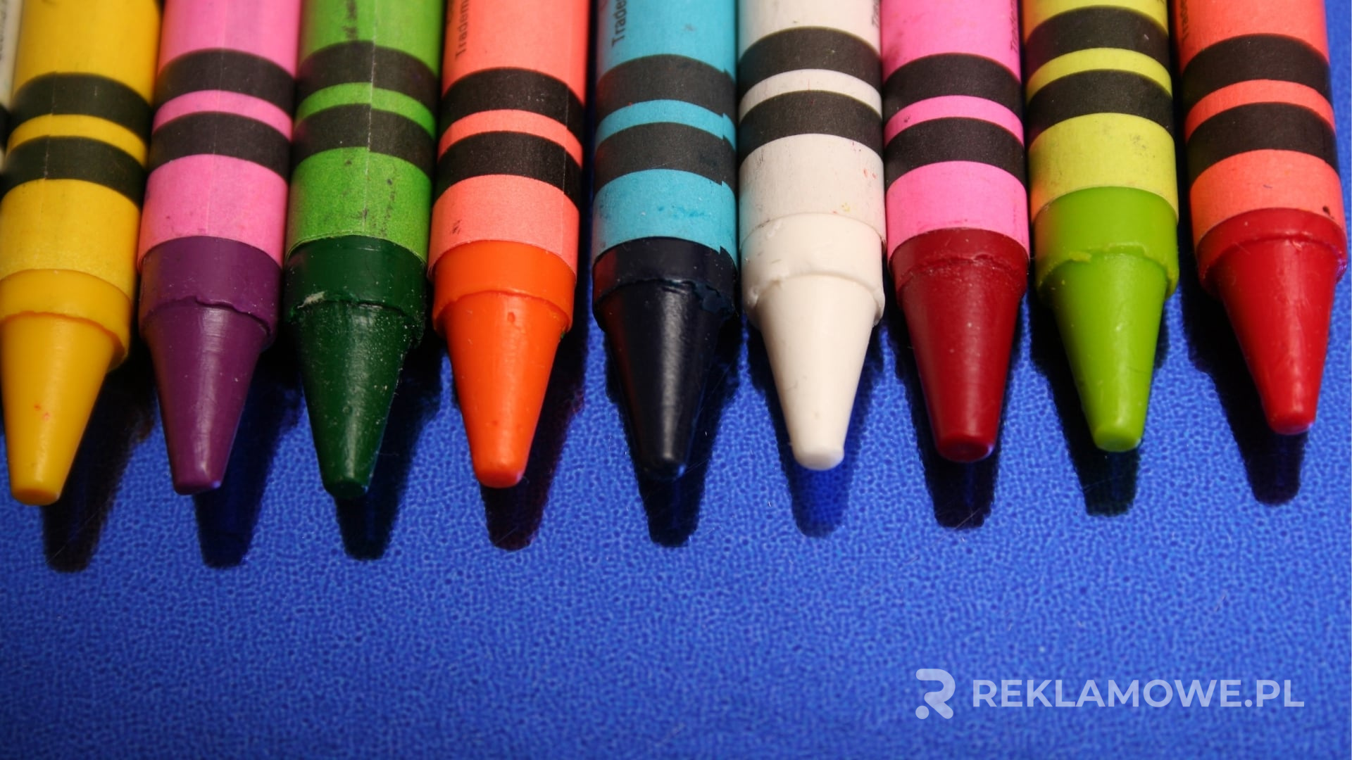 Kolorowe kredki reklamowe ułożone na biurku